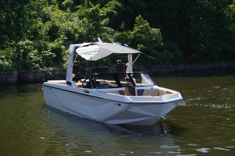 Slide: The Image of 2025 Nautique GS24 boat on a calm river, surrounded by lush greenery. - 5