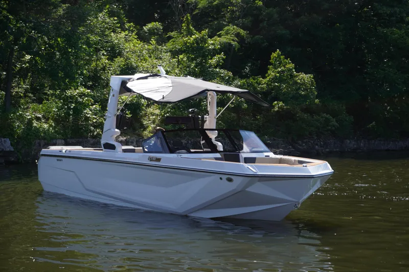 Slide: The Image of 2025 Nautique GS24 boat on a calm lake, surrounded by lush greenery. - 6