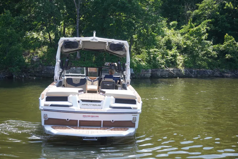 Slide: The Image of 2025 Nautique GS24 boat on a calm lake, surrounded by lush greenery. - 9