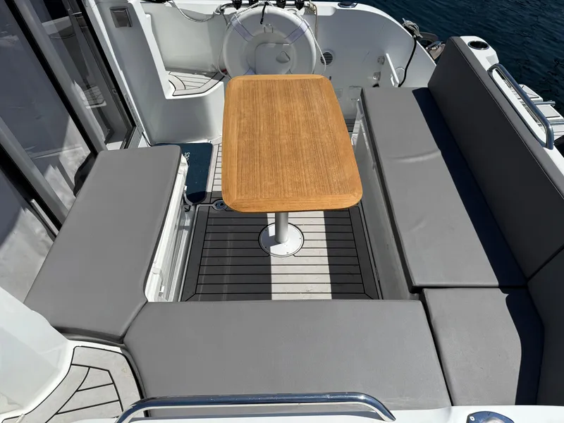 Slide: The Image of Beneteau Antares 8, 2021 model, featuring a cozy outdoor seating area with a wooden table. - 27
