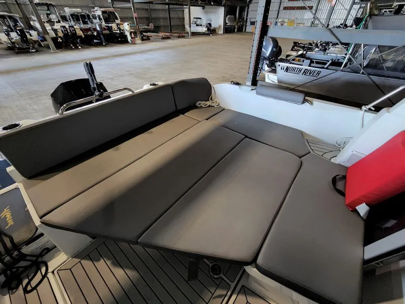 Slide: The Image of Interior view of 2021 Beneteau Antares 8 with cushioned seating in a boat showroom. - 28