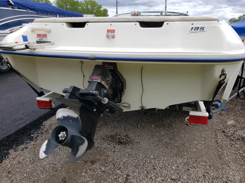 Slide: The Image of 1995 Sea Ray 195BR boat rear view with propeller, parked on gravel. - 2