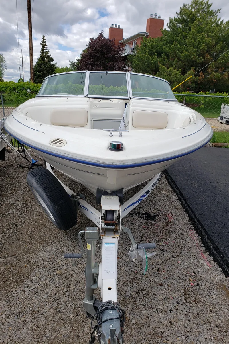 Slide: The Image of 1995 Sea Ray 195BR boat on trailer, parked outdoors, with trees and buildings in background. - 3