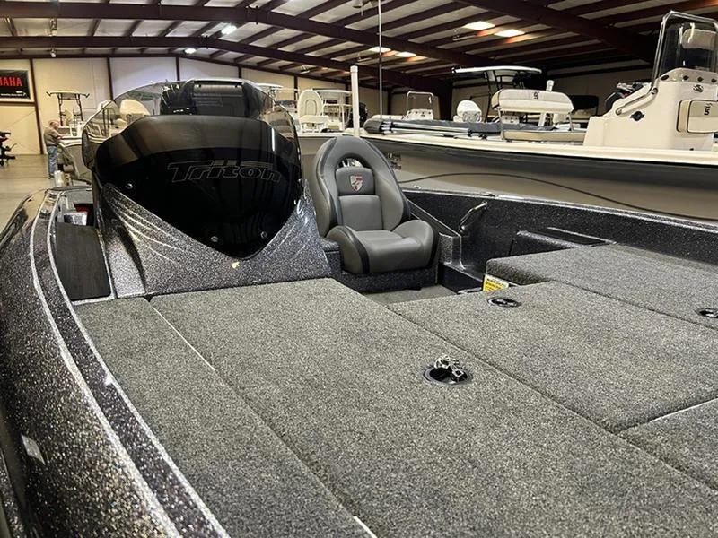 Slide: The Image of 2023 Triton 179 TrX boat interior with gray seating and spacious deck in showroom. - 4