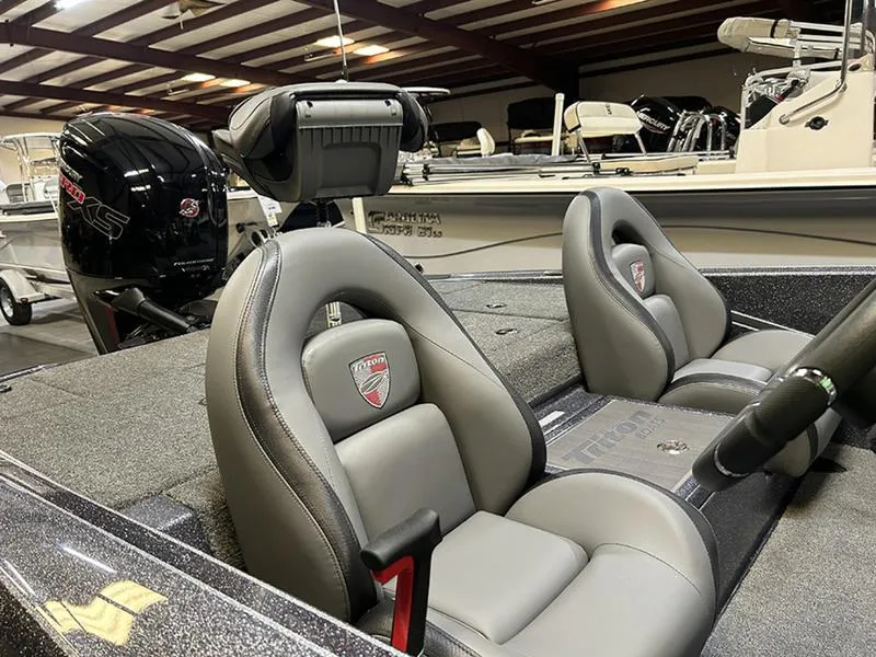 Slide: The Image of 2023 Triton 179 TrX boat interior with gray seats and powerful engine in showroom. - 7
