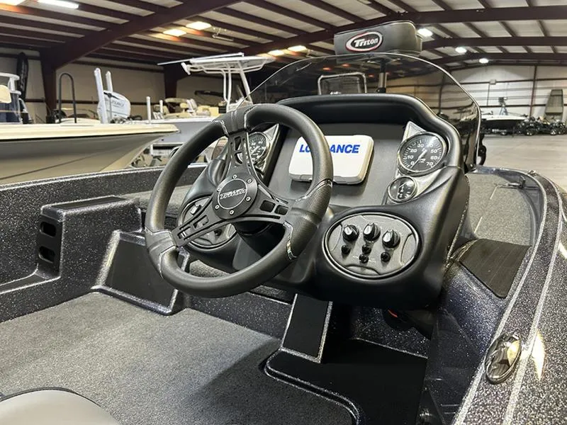 Slide: The Image of 2023 Triton 179 TrX boat dashboard with steering wheel and control panel in a showroom. - 8
