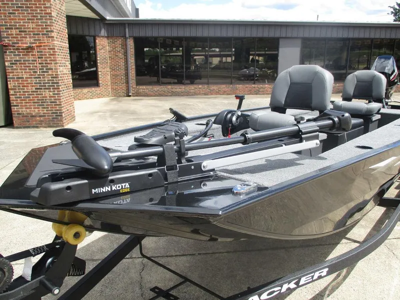 Slide: The Image of 2025 Tracker Panfish™ 17 boat with Minn Kota trolling motor, parked outside a building. - 4