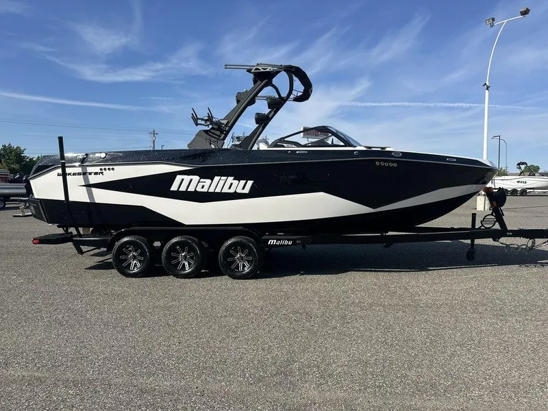 Slide: The Image of 2025 Malibu 25 LSV boat on trailer, black and white design, parked outdoors. - 1