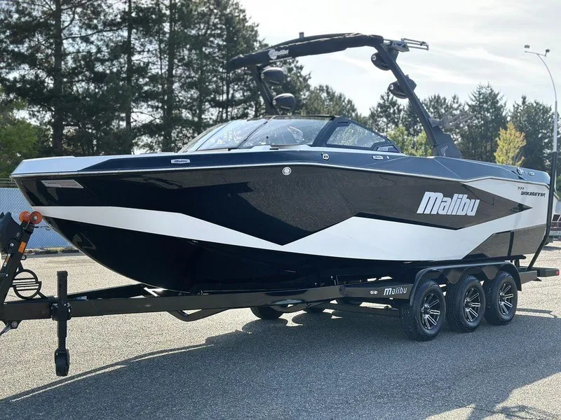 Slide: The Image of 2025 Malibu 25 LSV boat on trailer, sleek black and white design, parked outdoors. - 24