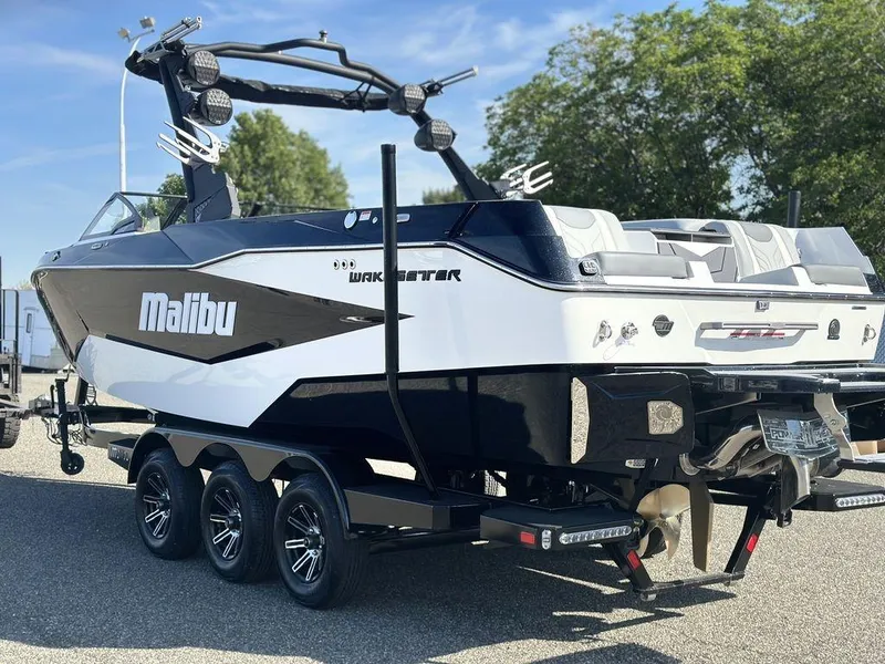 Slide: The Image of 2025 Malibu 25 LSV boat on trailer, sleek design, black and white color scheme. - 26