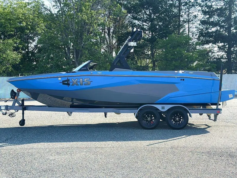 Slide: The Image of 2025 Axis A225 boat in blue and gray on a trailer, parked outdoors. - 24