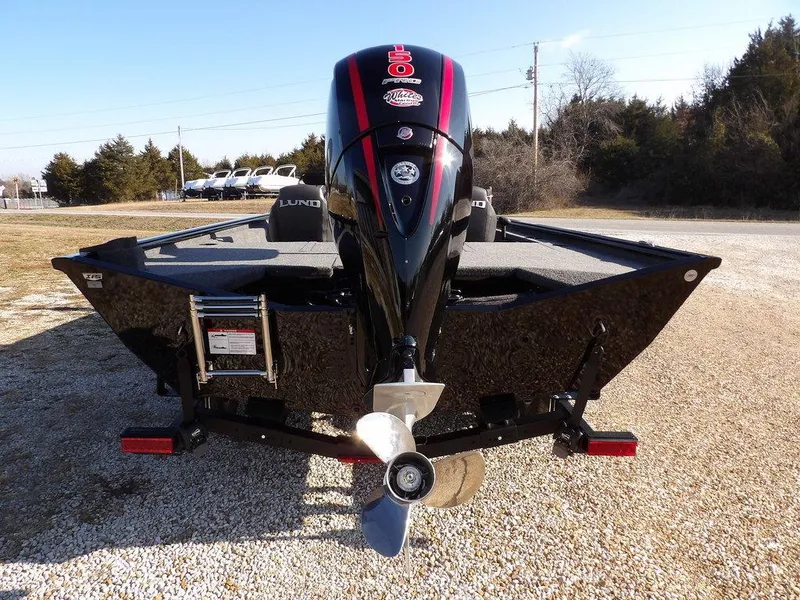 Slide: The Image of 2025 Lund 1975 Renegade SS boat with powerful outboard motor, parked on gravel. - 44