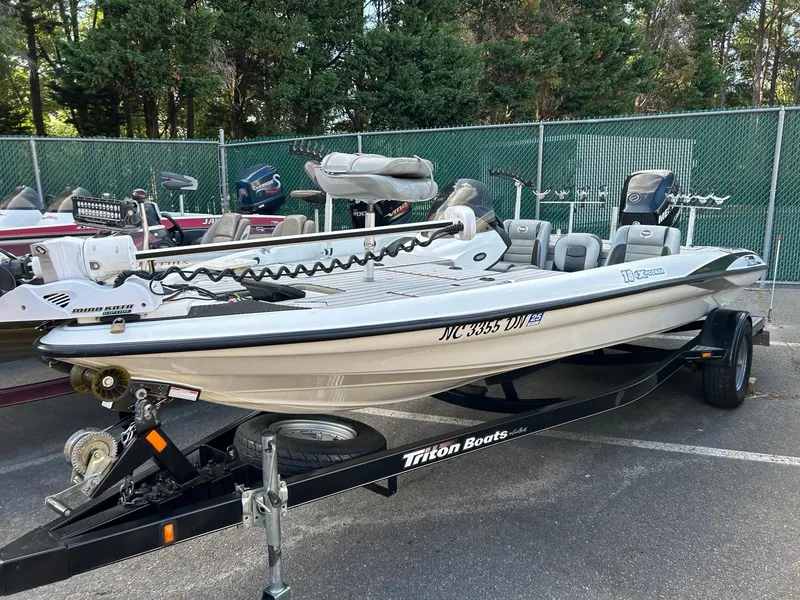 Slide: The Image of 2009 Triton 18 Explorer boat on trailer, parked outdoors near fence. - 0
