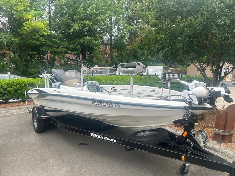 Slide: The Image of 2009 Triton 18 Explorer boat on trailer, parked outdoors with trees in background. - 1