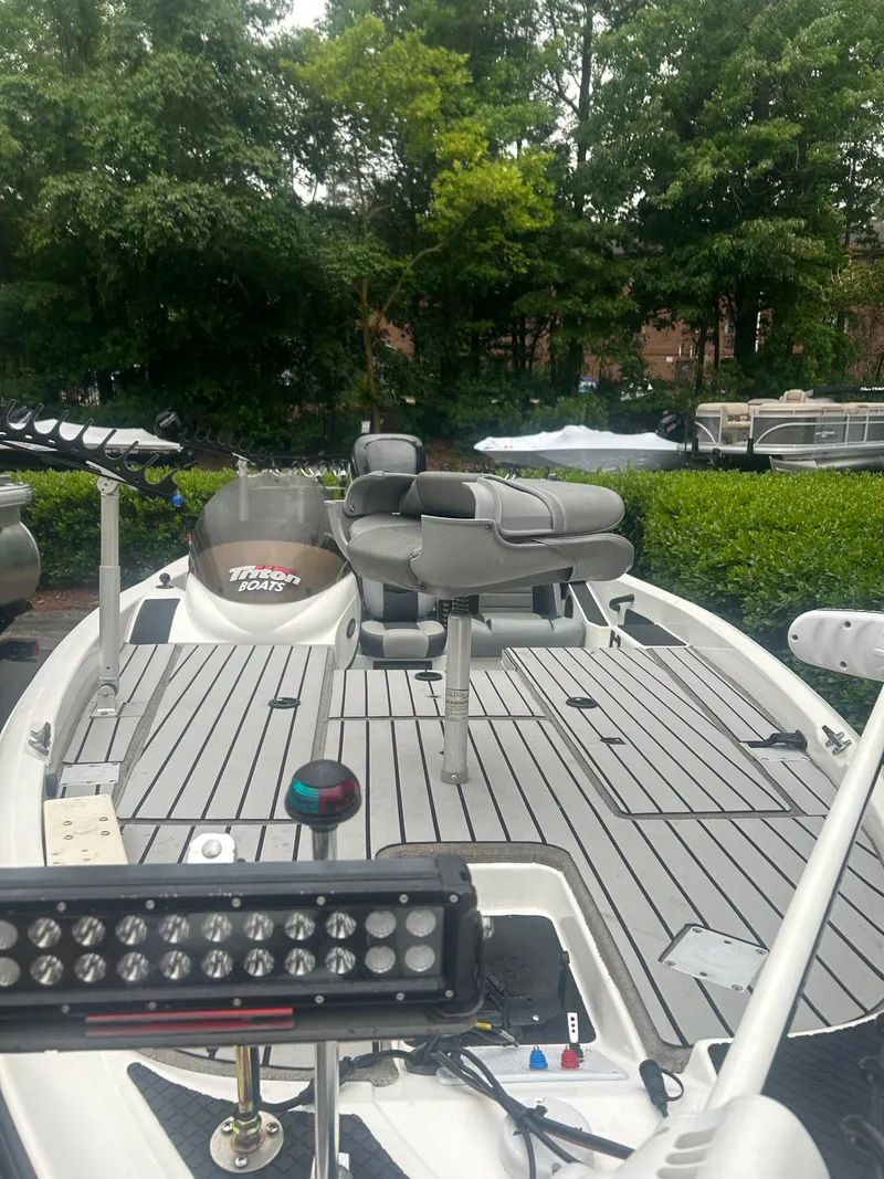 Slide: The Image of 2009 Triton 18 Explorer boat with seating and equipment, surrounded by greenery. - 2