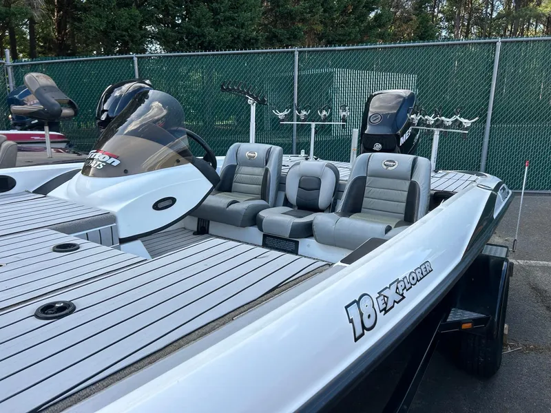 Slide: The Image of 2009 Triton 18 Explorer boat with seating, parked near a green fence. - 3