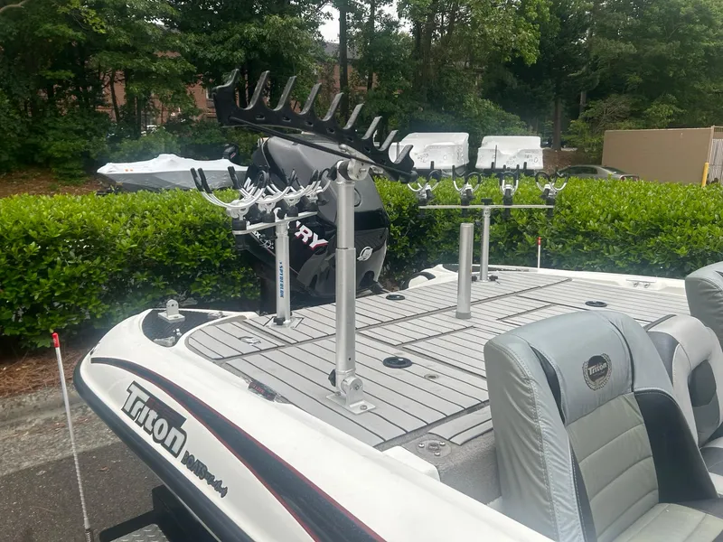 Slide: The Image of 2009 Triton 18 Explorer boat with fishing rod holders and seating, parked outdoors. - 6