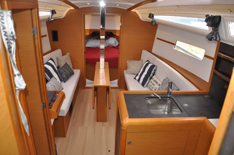 Slide: The Image of Interior of 2016 Jeanneau Sun Odyssey 349 sailboat, featuring cozy seating and compact kitchen area. - 23