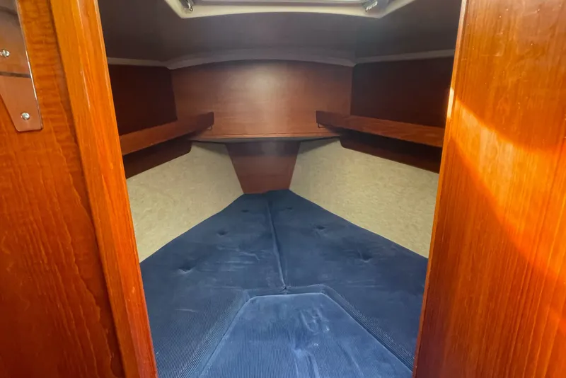 Slide: The Image of V-berth cabin interior of 1985 Contest 36S sailboat with blue cushions and wooden finish. - 10