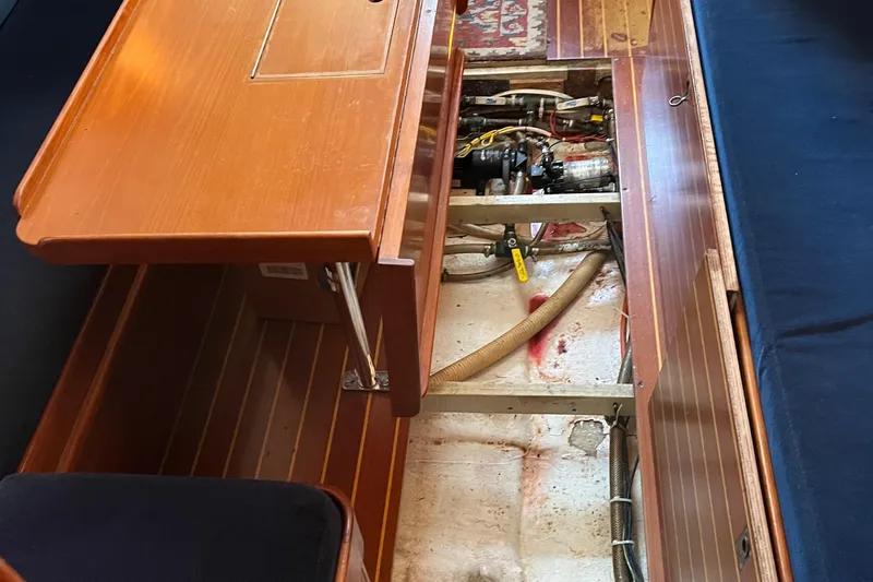 Slide: The Image of 1985 Contest 36S yacht interior showing engine compartment under wooden table. - 12