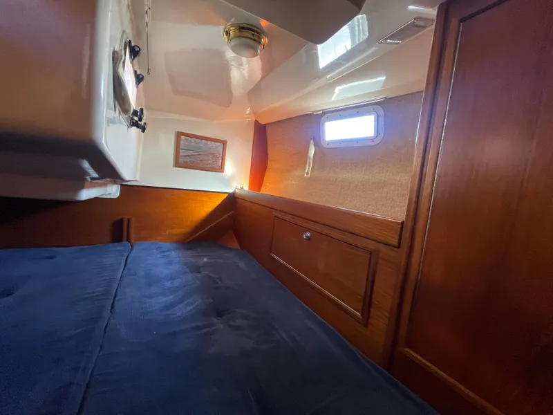 Slide: The Image of Cozy cabin interior of 1985 Contest 36S sailboat with wooden paneling and blue bedding. - 2