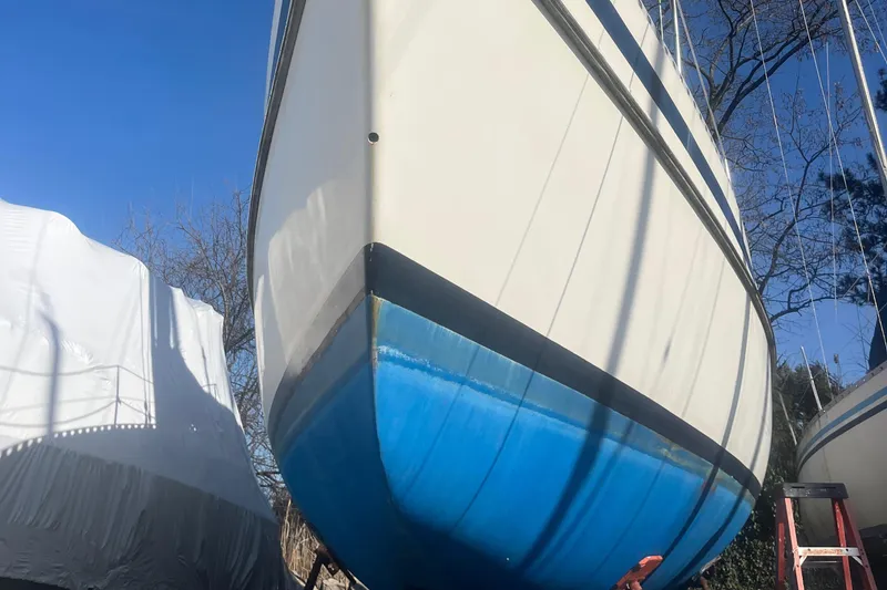 Slide: The Image of 1985 Contest 36S sailboat with blue hull, docked outdoors under clear sky. - 24