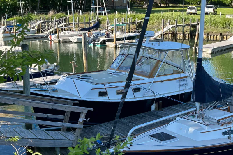 The Image of 1989 Fortier F-30 Hardtop boat docked in a marina with surrounding sailboats. - 0