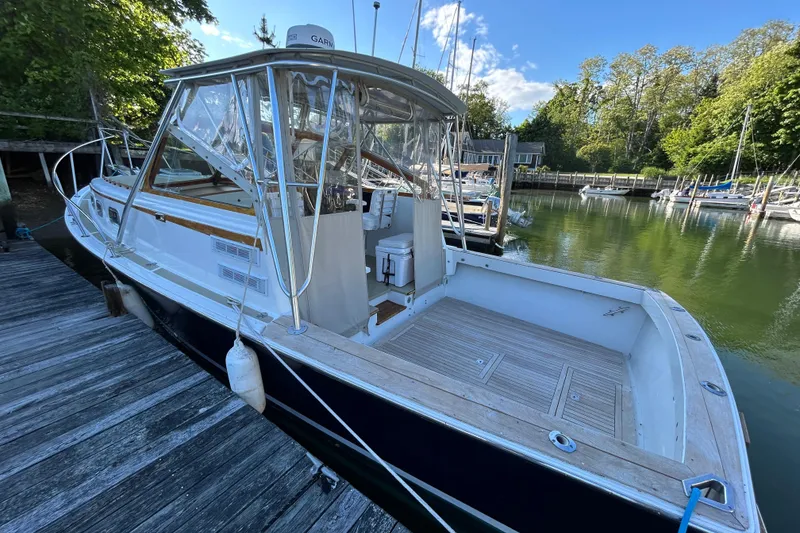 Slide: The Image of 1989 Fortier F-30 Hardtop boat docked in a serene marina setting. - 1