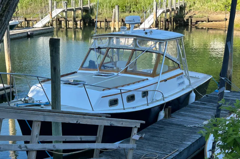 Slide: The Image of 1989 Fortier F-30 Hardtop boat docked in a serene marina setting. - 12