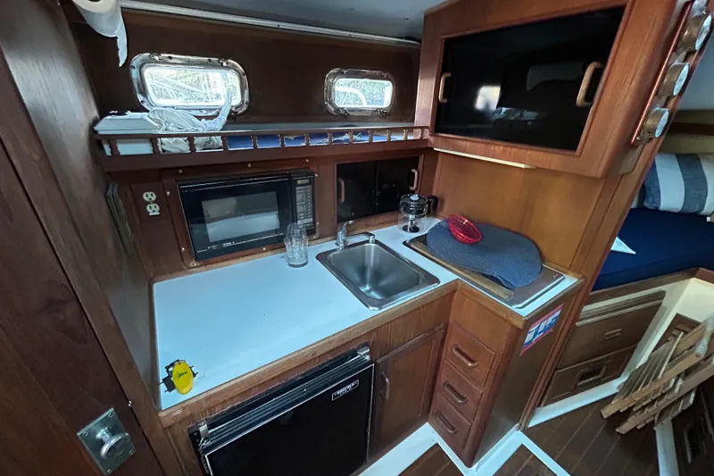 Slide: The Image of 1989 Fortier F-30 Hardtop boat interior with kitchenette, sink, microwave, and wooden cabinetry. - 3