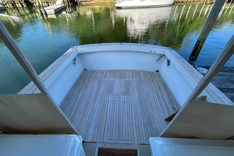 Slide: The Image of 1989 Fortier F-30 Hardtop boat deck with wooden flooring, docked by calm waters. - 9