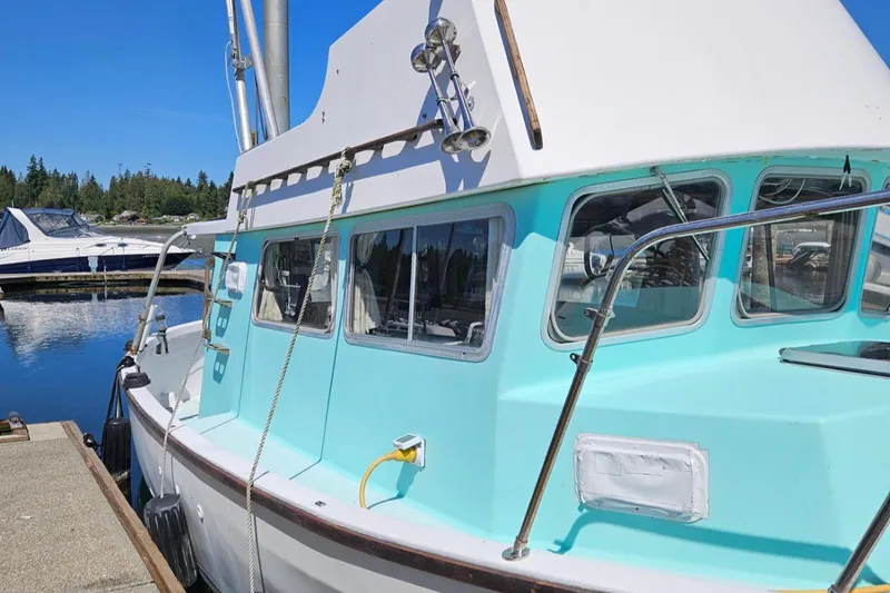 Slide: The Image of 1975 Monterey Diesel Cruiser Trawler docked at marina, featuring turquoise cabin and clear windows. - 28