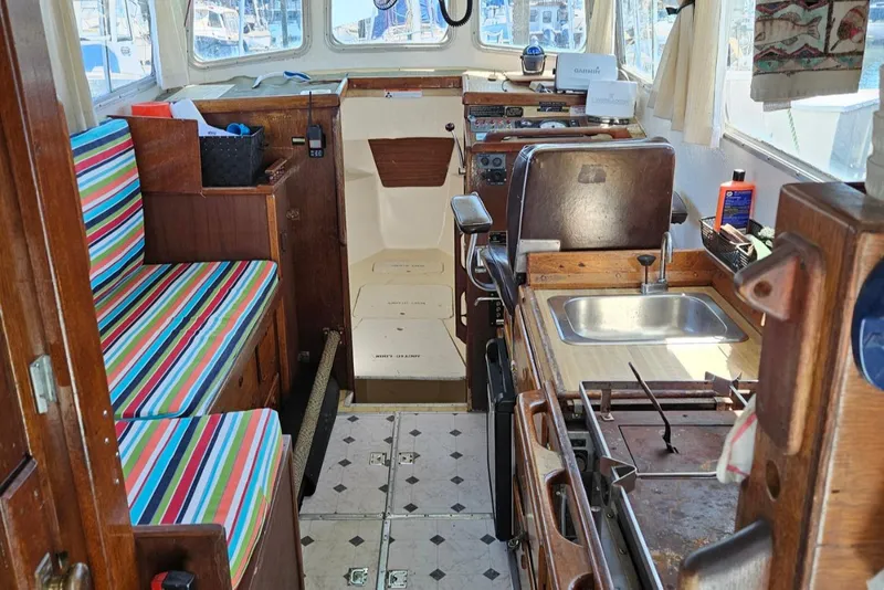Slide: The Image of 1975 Monterey Diesel Cruiser trawler interior with striped seating, kitchenette, and navigation area. - 3