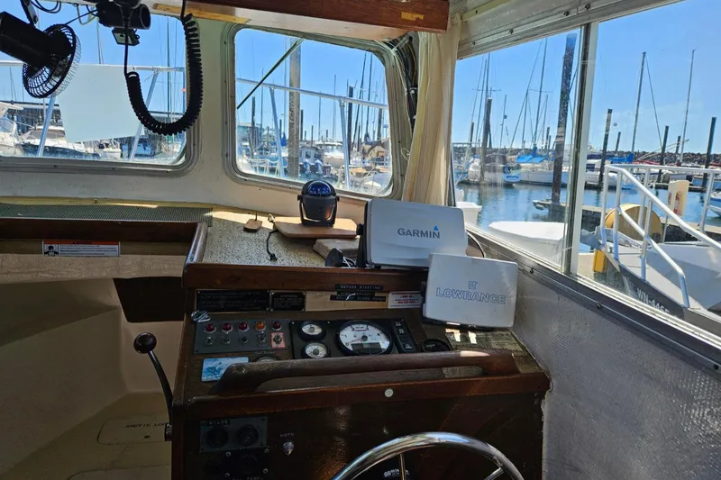 Slide: The Image of 1975 Monterey Diesel Cruiser trawler cockpit with navigation equipment, docked at a marina. - 6