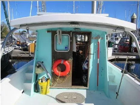 Slide: The Image of 1975 Monterey Diesel Cruiser Trawler docked, featuring a vibrant turquoise cabin and safety equipment. - 7