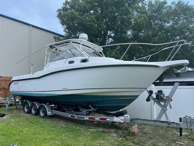 Slide: The Image of 2008 Boston Whaler 305 Conquest boat on trailer, parked outdoors near a building. - 0