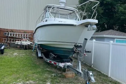 Slide: The Image of 2008 Boston Whaler 305 Conquest boat on trailer, parked in a yard. - 1