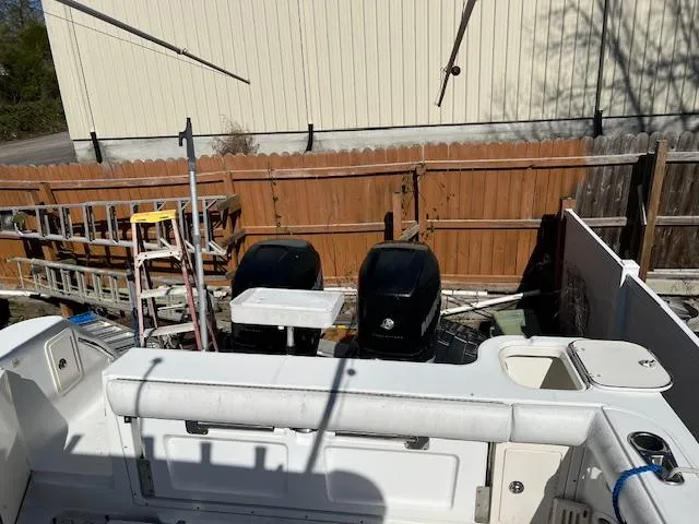 Slide: The Image of 2008 Boston Whaler 305 Conquest boat with dual outboard engines, docked near a wooden fence. - 11