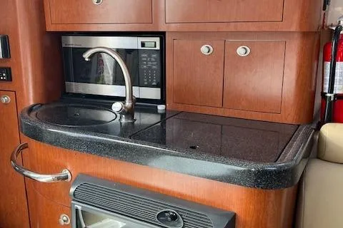 Slide: The Image of 2008 Boston Whaler 305 Conquest galley with sink, microwave, and storage cabinets. - 15