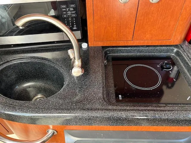 Slide: The Image of 2008 Boston Whaler 305 Conquest kitchen with sink, stovetop, and wooden cabinetry. - 17