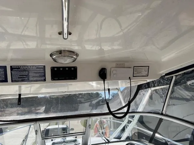 Slide: The Image of 2008 Boston Whaler 305 Conquest boat interior, featuring control panel and overhead light. - 8