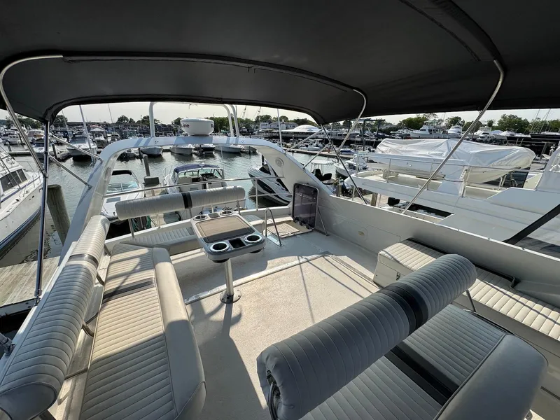 Slide: The Image of 1989 Birchwood 62 Cockpit Motor Yacht interior with seating and table, docked at marina. - 10