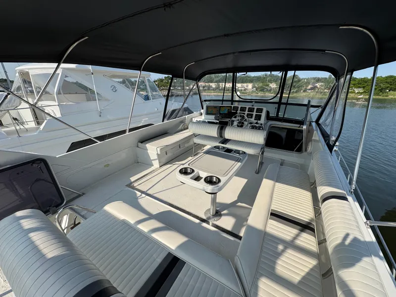 Slide: The Image of 1989 Birchwood 62 Cockpit Motor Yacht interior with seating and helm, docked by the water. - 11