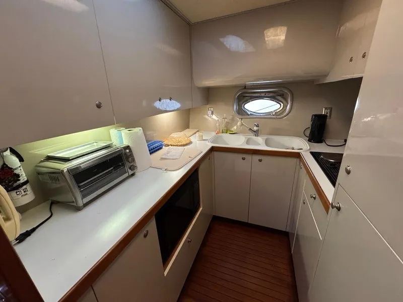 Slide: The Image of 1989 Birchwood 62 Cockpit Motor Yacht kitchen with modern appliances and wooden flooring. - 26