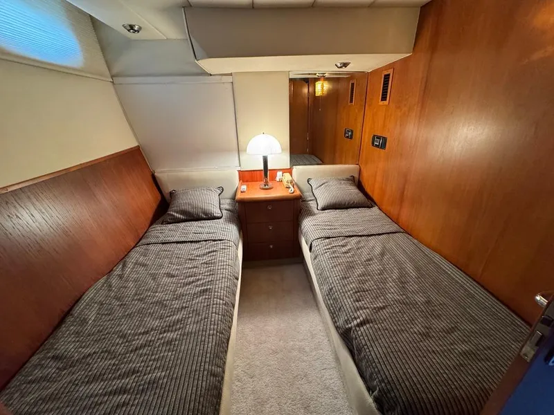 Slide: The Image of Twin cabin in 1989 Birchwood 62 Cockpit Motor Yacht with wooden paneling and bedside lamp. - 29