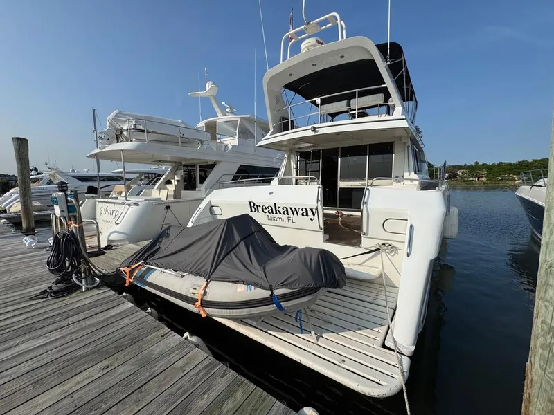 Slide: The Image of 1989 Birchwood 62 Cockpit Motor Yacht docked, featuring covered equipment on the deck. - 4