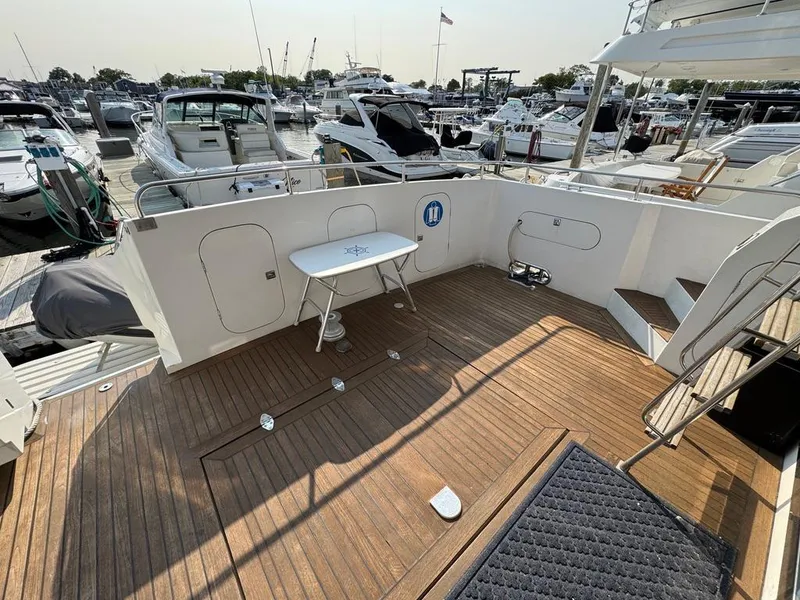 Slide: The Image of 1989 Birchwood 62 Cockpit Motor Yacht with spacious wooden deck at marina. - 7