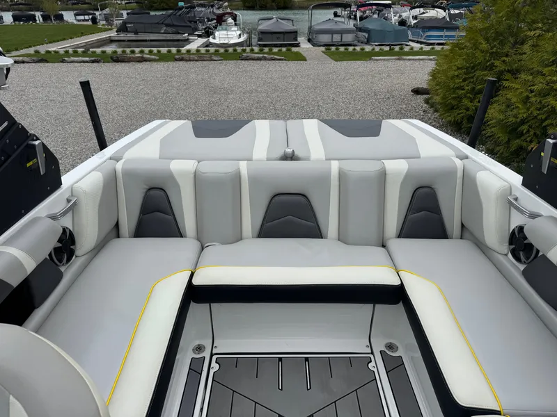 Slide: The Image of 2018 Malibu VLX boat interior with gray and white seating, docked near other boats. - 11