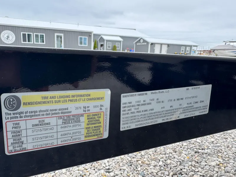Slide: The Image of Tire and loading information on a 2018 Malibu VLX trailer, with buildings in the background. - 14