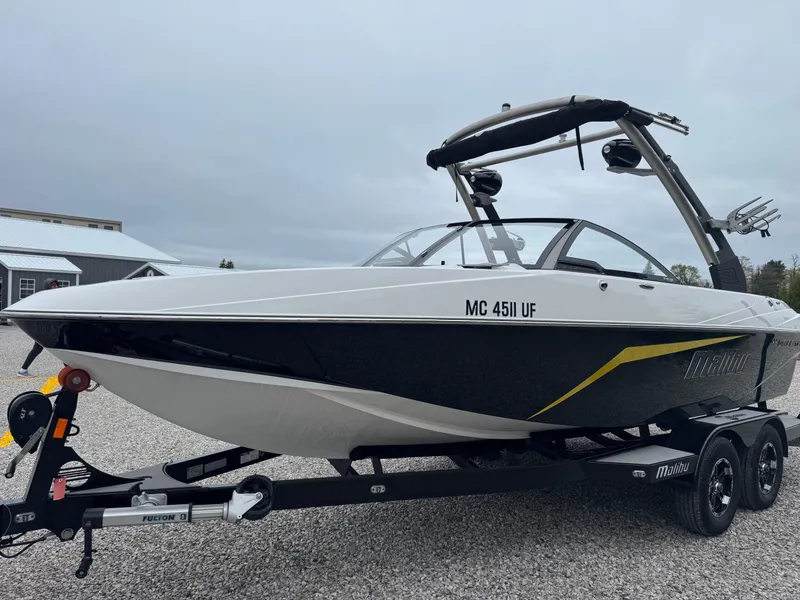 Slide: The Image of 2018 Malibu VLX boat on trailer, black and white design, overcast sky background. - 4